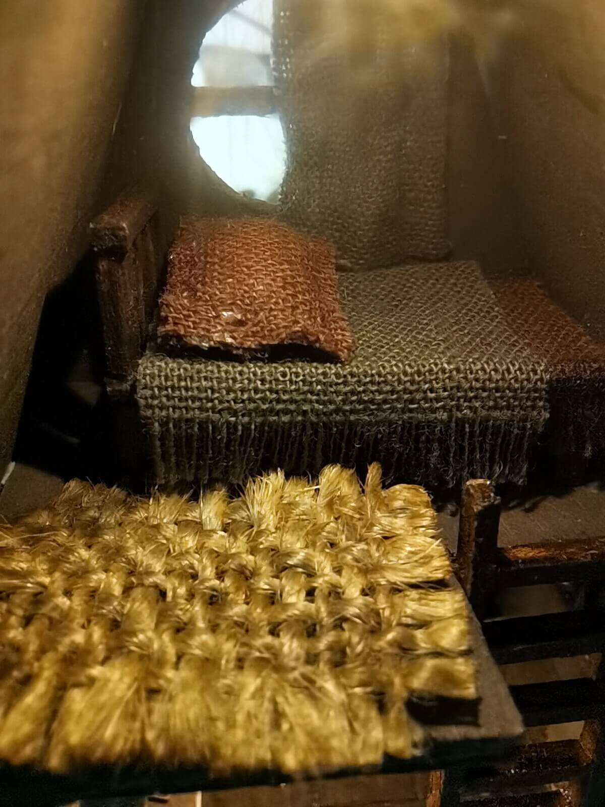 This miniature wooden treehouse exudes a whimsical, fairy-tale charm. It features a cozy loft bed under a slanted roof, accessible by a rustic wooden ladder. Warm lighting illuminates the intricate interior details, including a tiny desk, books, and woven fabrics, showcasing the delicate craftsmanship and magical ambiance of this enchanting creation.