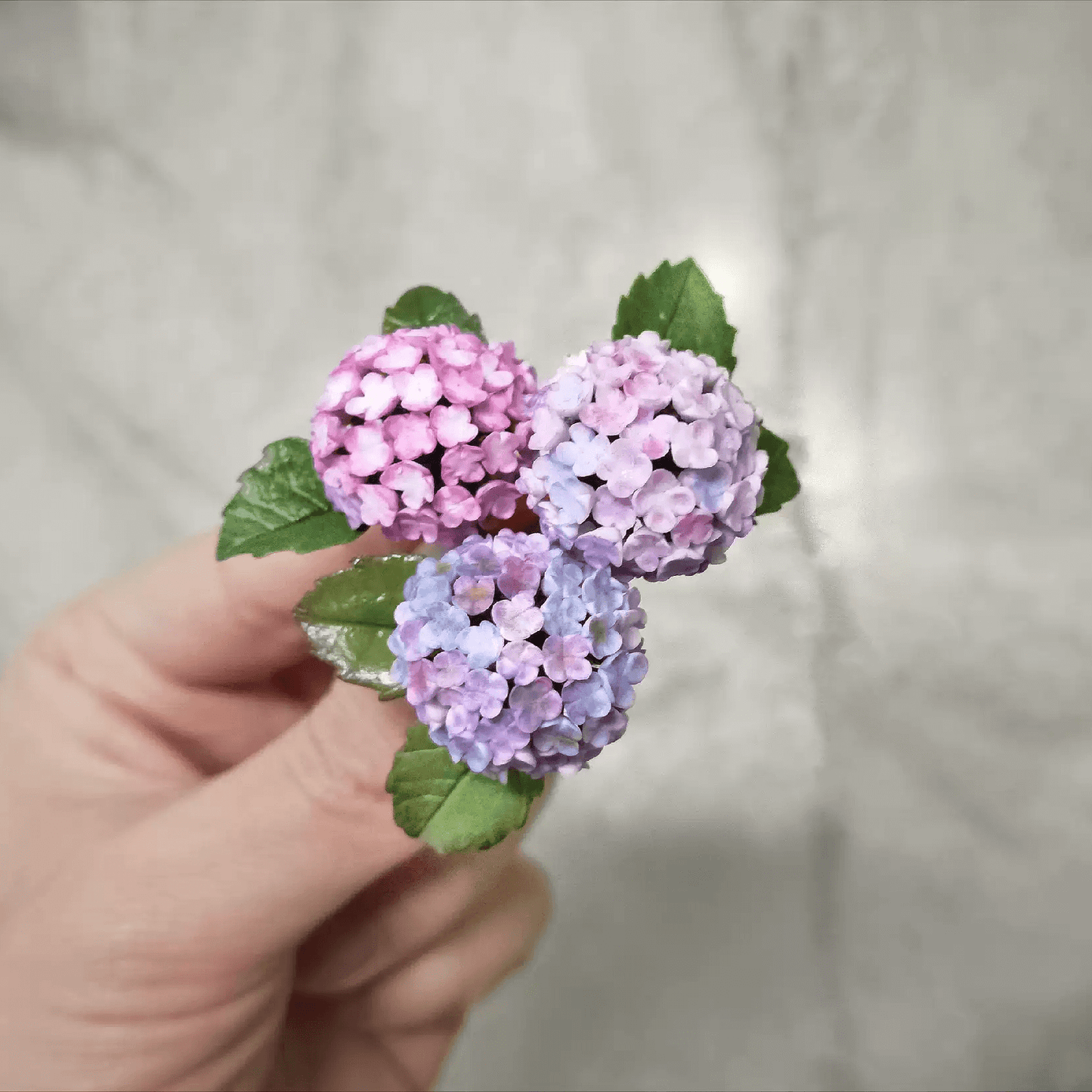 Hydrangeas are deciduous shrubs with flowers in terminal, round or umbrella-shaped clusters in colors of white, pink, or blue, or even purple. Scale: 1:6; 1:12 Material: Handmade from Clay Default Color: Random A variety of colors are available, choose your favorite color and make a note.
