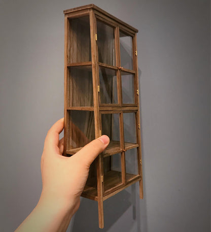 Created with versatility in mind, this display shelf and bookcase may be used in the dollhouse kitchen as a cabinet, in the study as a bookcase or in the living room as a bookcase or display cabinet. Color/ Finish: Cherry wood or Dark walnut