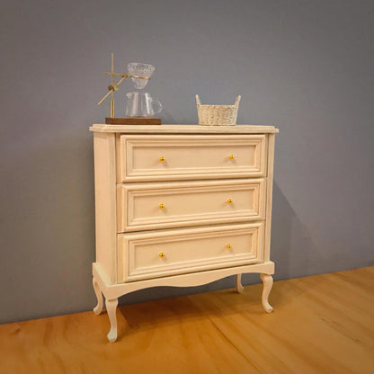 It boasts three spacious drawers, providing ample storage for your essentials. Supported by graceful cabriole legs, this dollhouse chest of drawers combines classic French design with functional elegance, making it a perfect addition to any dollhouse bedroom or living area seeking a touch of refined style and historical charm.