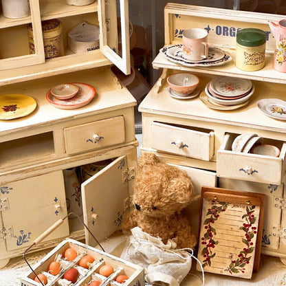 Add a touch of vintage charm to your dollhouse with this Miniature Vintage Kitchen Cabinet with Drawers and Shelves Kit. This beautifully crafted cabinet features multiple drawers and an open shelf, perfect for displaying or storing miniature kitchen items like plates, cups, and utensils. The charming floral decorations and soft yellow finish make this piece a perfect addition to any dollhouse kitchen, dining room, or living room.