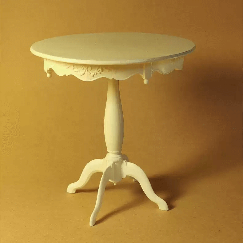 The Miniature Round Dining Side Table with Carved and Quadripod Base boasts a serene round top with subtly serpentine lines. Its timeless appeal is enhanced by slight distressing, lending an inviting, lived-in feel that speaks volumes of its rich history and careful craftsmanship.