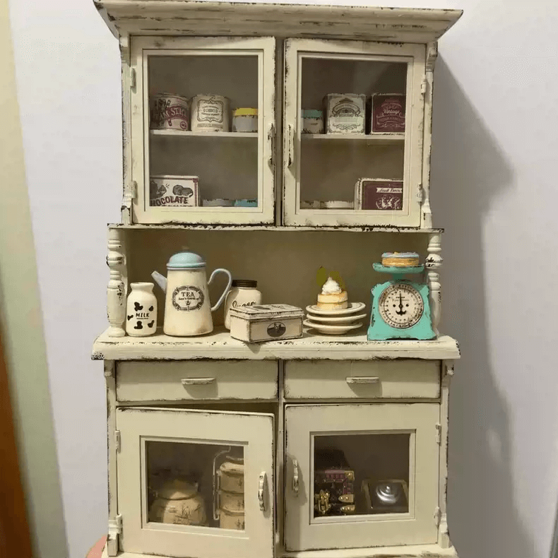 Add a touch of vintage elegance to your dollhouse with this Miniature Shabby Chic Kitchen Sideboard Cupboard Dresser Cabinet Kit. This beautifully crafted piece combines a charming sideboard with a cupboard and dresser, offering both display and storage options. The cabinet features doors for showcasing small items, while the lower section includes drawers for organizing your mini treasures.