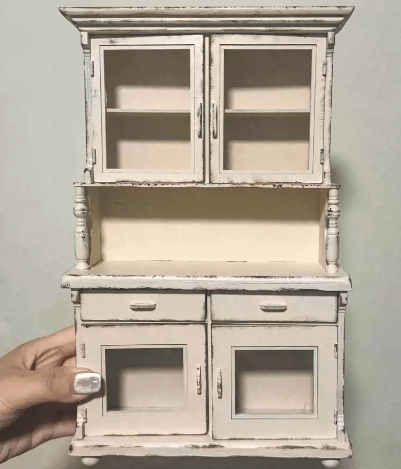 Add a touch of vintage elegance to your dollhouse with this Miniature Shabby Chic Kitchen Sideboard Cupboard Dresser Cabinet Kit. This beautifully crafted piece combines a charming sideboard with a cupboard and dresser, offering both display and storage options. The cabinet features doors for showcasing small items, while the lower section includes drawers for organizing your mini treasures.