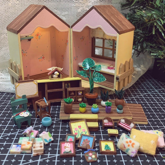 This foldable miniature dollhouse opens up to reveal two charming rooms filled with detailed, removable furniture. One side features an artistic studio with a cozy easel, plant decor, and a workspace, while the other side offers a relaxing bedroom with colorful pillows, a plush bed, and a vibrant window. Each piece, from the tiny bookshelves to the small plants, is meticulously crafted, making it an ideal addition for collectors or anyone who loves unique, interactive designs.