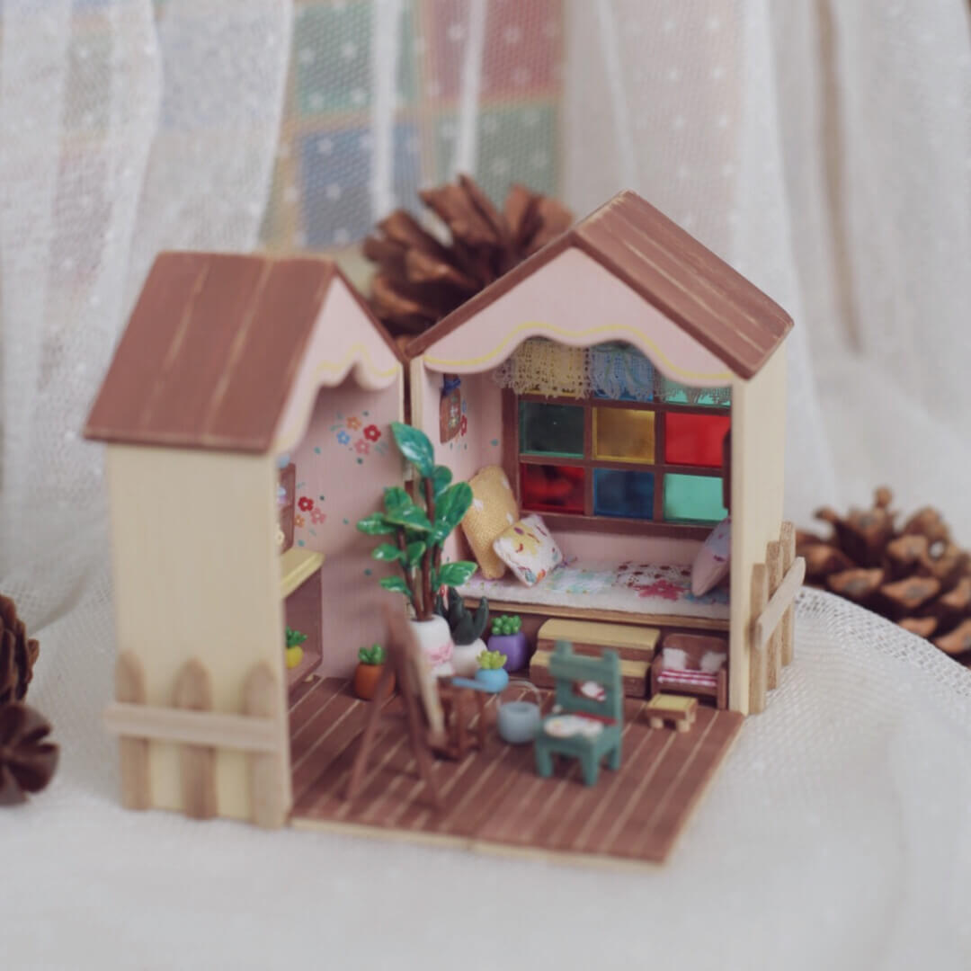 This foldable miniature dollhouse opens up to reveal two charming rooms filled with detailed, removable furniture. One side features an artistic studio with a cozy easel, plant decor, and a workspace, while the other side offers a relaxing bedroom with colorful pillows, a plush bed, and a vibrant window. Each piece, from the tiny bookshelves to the small plants, is meticulously crafted, making it an ideal addition for collectors or anyone who loves unique, interactive designs.