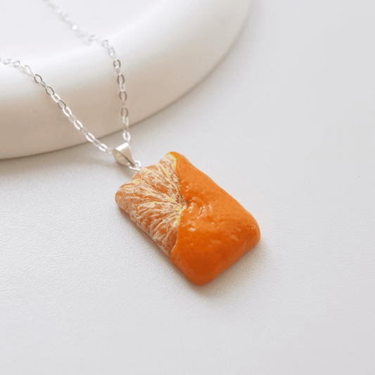 Cute realistic square half-peeled tangerine necklace with sterling silver chain. The tangerine are made with polymer clay and then finished with a gloss varnish. The necklace are made from high-quality materials and are durable, but should not be put in aggressive environments like excessive moisture, chemicals or perfume.