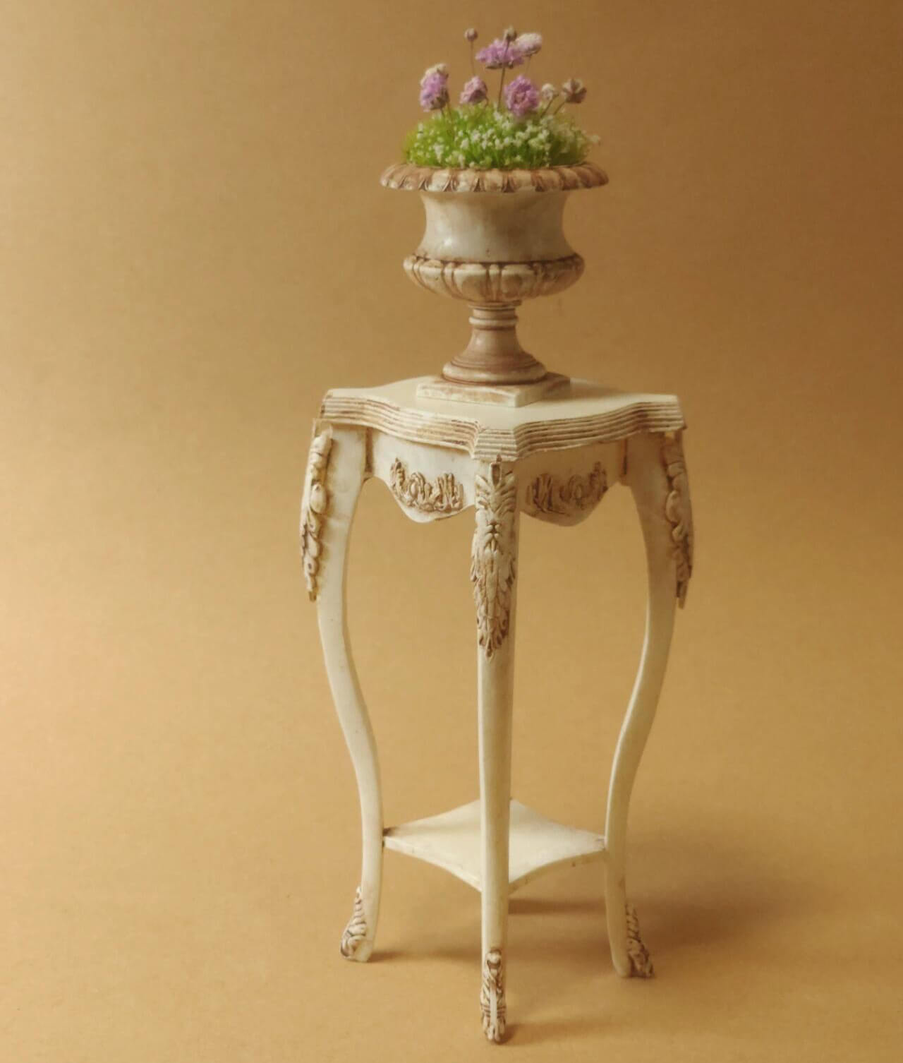 This Miniature Artisan Flower Stand Plant Shelf Side Table Kit for Dollhouses is a versatile and elegant addition to any dollhouse setting. Designed with intricate carvings and gracefully curved legs, this piece serves as a charming flower stand, a practical plant shelf, or a stylish side table. Its timeless vintage aesthetic makes it ideal for dollhouse living rooms, gardens, patios, or entryways.