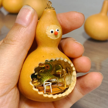 This adorable handcrafted gourd features a miniature bedroom tucked inside, complete with a cozy bed, a bedside table, and warm lighting. The intricate details, from the textured bedspread to the tiny furniture, create a whimsical and inviting space. Topped with a cheerful face, this gourd transforms into a charming piece of art that feels alive with personality and creativity.