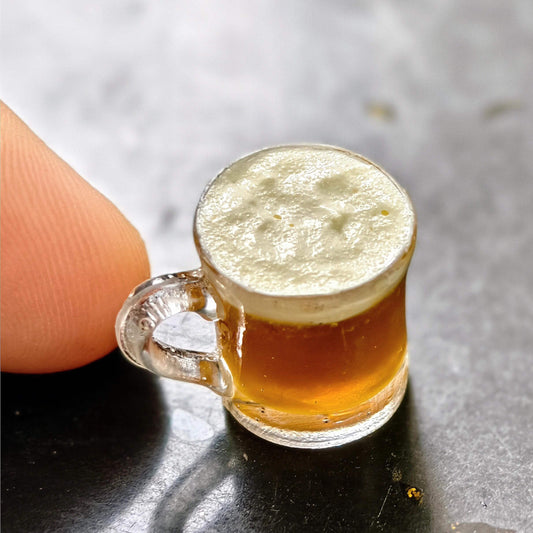 A miniature mug filled with pale beer or ale with a nice head of foam on top. The perfect drink for your dolls.