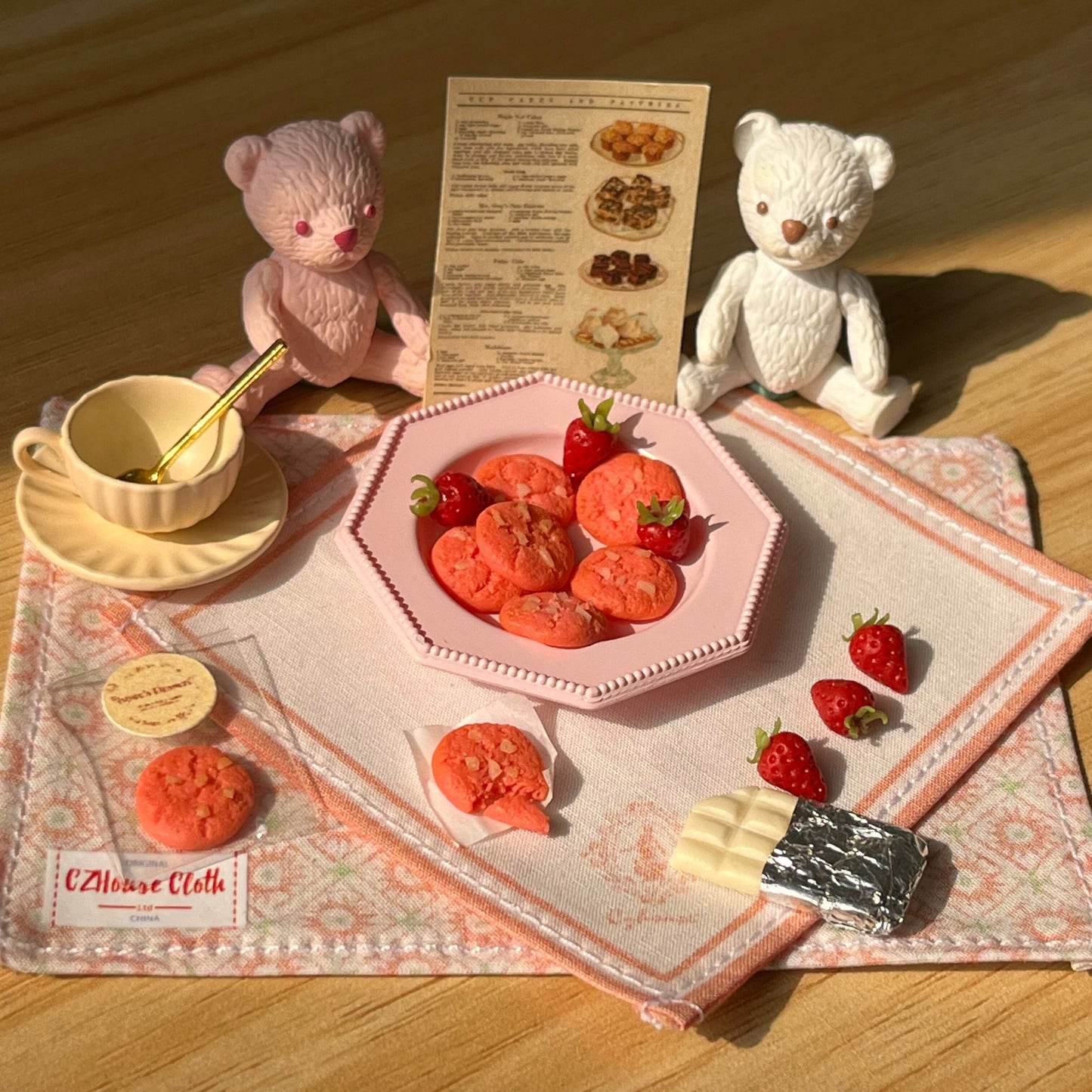 The set includes: 2 placemats, 1 plate, 8 strawberry cookies, 1 coffee cup set, 6 strawberries, and 1 white chocolate. The bear is not included. Material: Clay