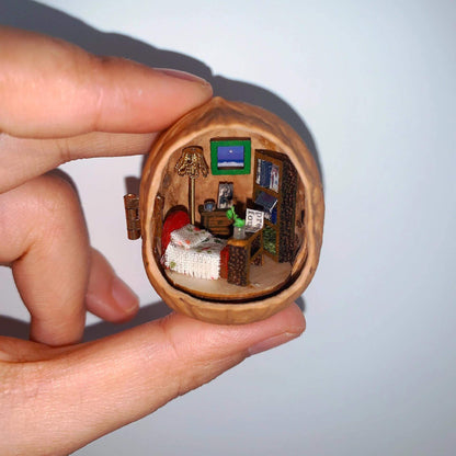 This walnut shell contains a charmingly detailed miniature bedroom. It features a cozy bed with a textured blanket, a tiny bookshelf stacked with books, a warm floor lamp, and a tiny potted plant. The soft lighting and carefully crafted details create a peaceful and intimate ambiance, perfect for a quiet escape.