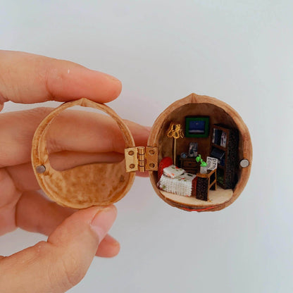 This walnut shell contains a charmingly detailed miniature bedroom. It features a cozy bed with a textured blanket, a tiny bookshelf stacked with books, a warm floor lamp, and a tiny potted plant. The soft lighting and carefully crafted details create a peaceful and intimate ambiance, perfect for a quiet escape.