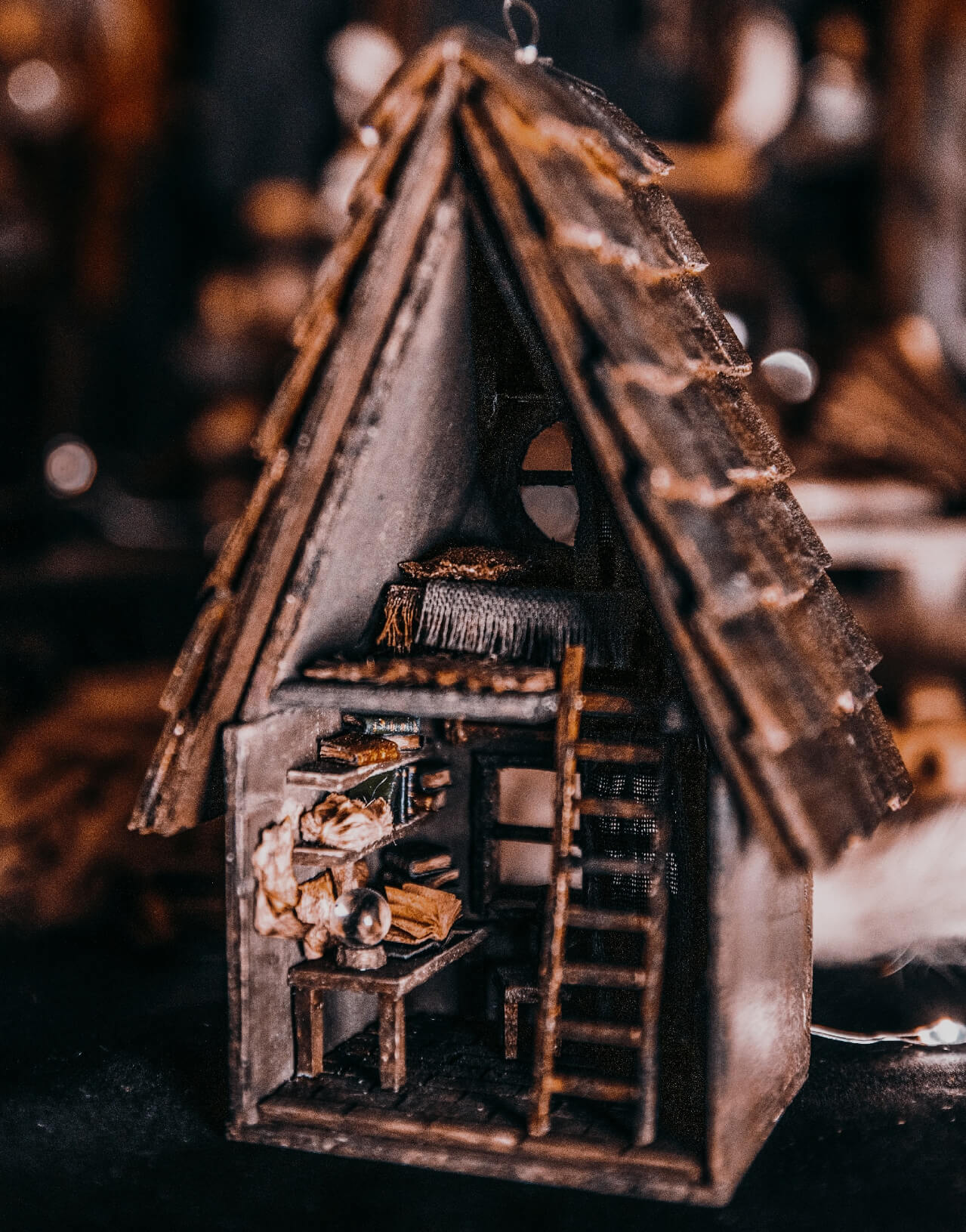 This miniature wooden treehouse exudes a whimsical, fairy-tale charm. It features a cozy loft bed under a slanted roof, accessible by a rustic wooden ladder. Warm lighting illuminates the intricate interior details, including a tiny desk, books, and woven fabrics, showcasing the delicate craftsmanship and magical ambiance of this enchanting creation.