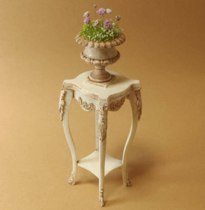 This Miniature Artisan Flower Stand Plant Shelf Side Table Kit for Dollhouses is a versatile and elegant addition to any dollhouse setting. Designed with intricate carvings and gracefully curved legs, this piece serves as a charming flower stand, a practical plant shelf, or a stylish side table. Its timeless vintage aesthetic makes it ideal for dollhouse living rooms, gardens, patios, or entryways.