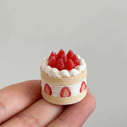 This charming miniature dessert display case is a sweet-tooth's dream brought to life. Featuring perfectly detailed strawberry shortcakes and pancake, each creation looks as delectable as the real thing. The rustic white display cabinet adds a cozy bakery vibe, enhancing the charm of these handcrafted treats. Every element, from the whipped cream to the vibrant strawberries, showcases the meticulous artistry and attention to detail.