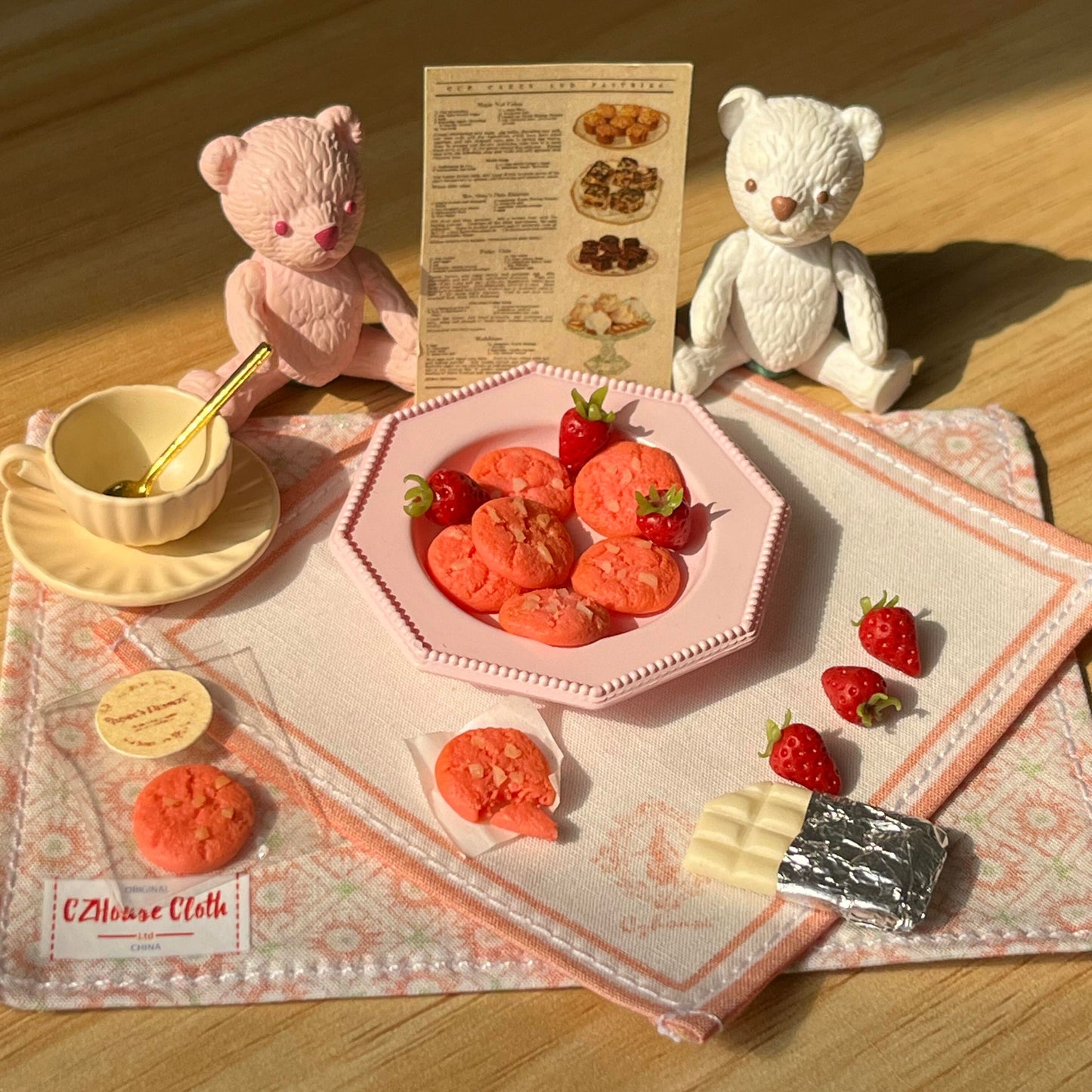 The set includes: 2 placemats, 1 plate, 8 strawberry cookies, 1 coffee cup set, 6 strawberries, and 1 white chocolate. The bear is not included. Material: Clay