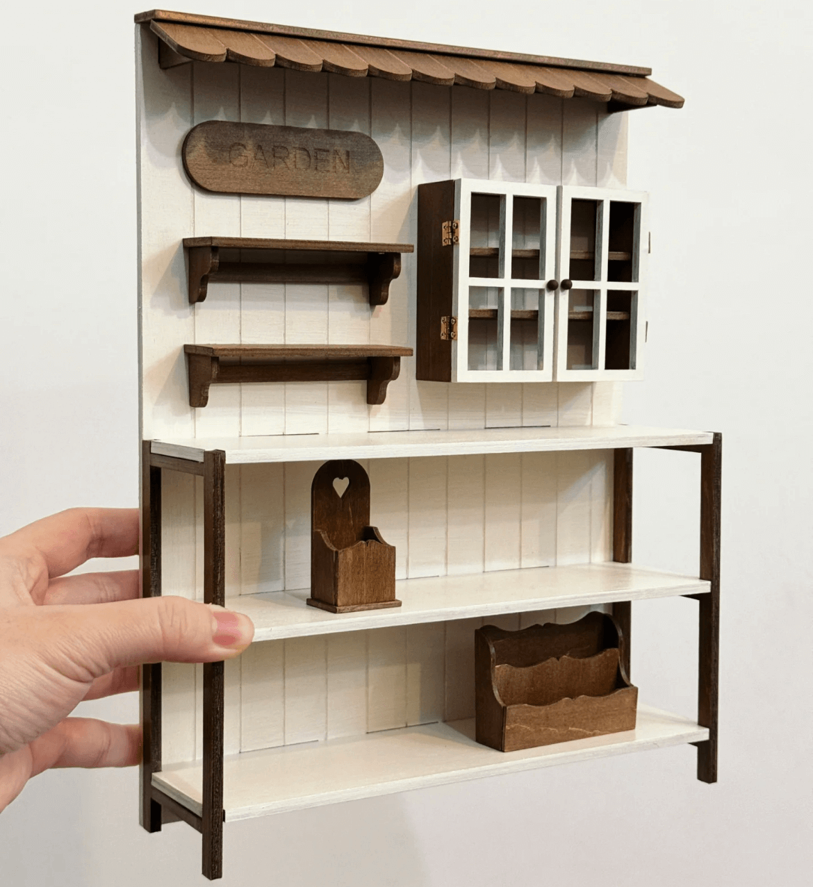 Add a charming touch of rustic elegance to your dollhouse with this Miniature Wooden Garden Shop Display Shelf Kit. Designed with intricate details, this piece features a classic garden shop look, complete with shelves for display and storage compartments. The roof adds a cozy, inviting feel, while the functional shelves are perfect for showcasing miniature plants, garden tools, and other tiny treasures.