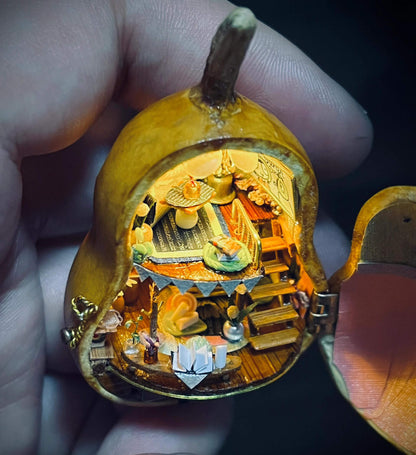 This intricate diorama captures a magical miniature home inside a gourd. The multi-level design showcases a cozy bedroom, a charming dining setup, and whimsical decorations. Adorned with delicate bunting, flowers, books, and candles, every detail exudes warmth and creativity. This enchanting craft is a tiny masterpiece that feels alive with stories waiting to unfold.