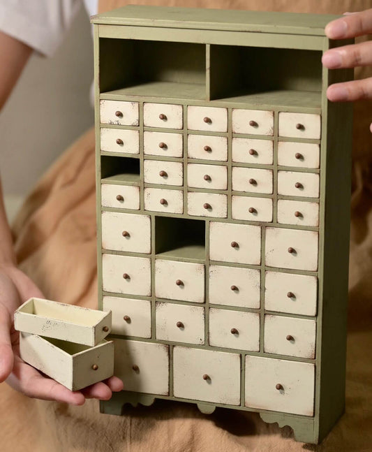 Bring a rustic touch of country charm to your dollhouse with this Miniature Wooden Farmhouse Garden Storage Cabinet Kit. Featuring drawers and an open top storage area, this versatile piece is perfect for organizing miniature gardening tools, seeds, small plants, or decorative items. Its green and white farmhouse design adds a cozy, natural feel to any miniature garden, kitchen, or workshop scene.