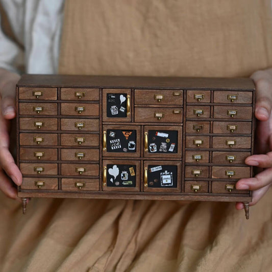 Inspired by old-fashioned cabinets used in apothecaries to store spices and other ingredients, this elegant miniature chest of drawers is a unique addition to both classic and modern interiors and can be used in a dollhouse bedroom or any living space as striking object of functional decor. Default Color/ Finish: Brown Styles: Vintage Material: Wood