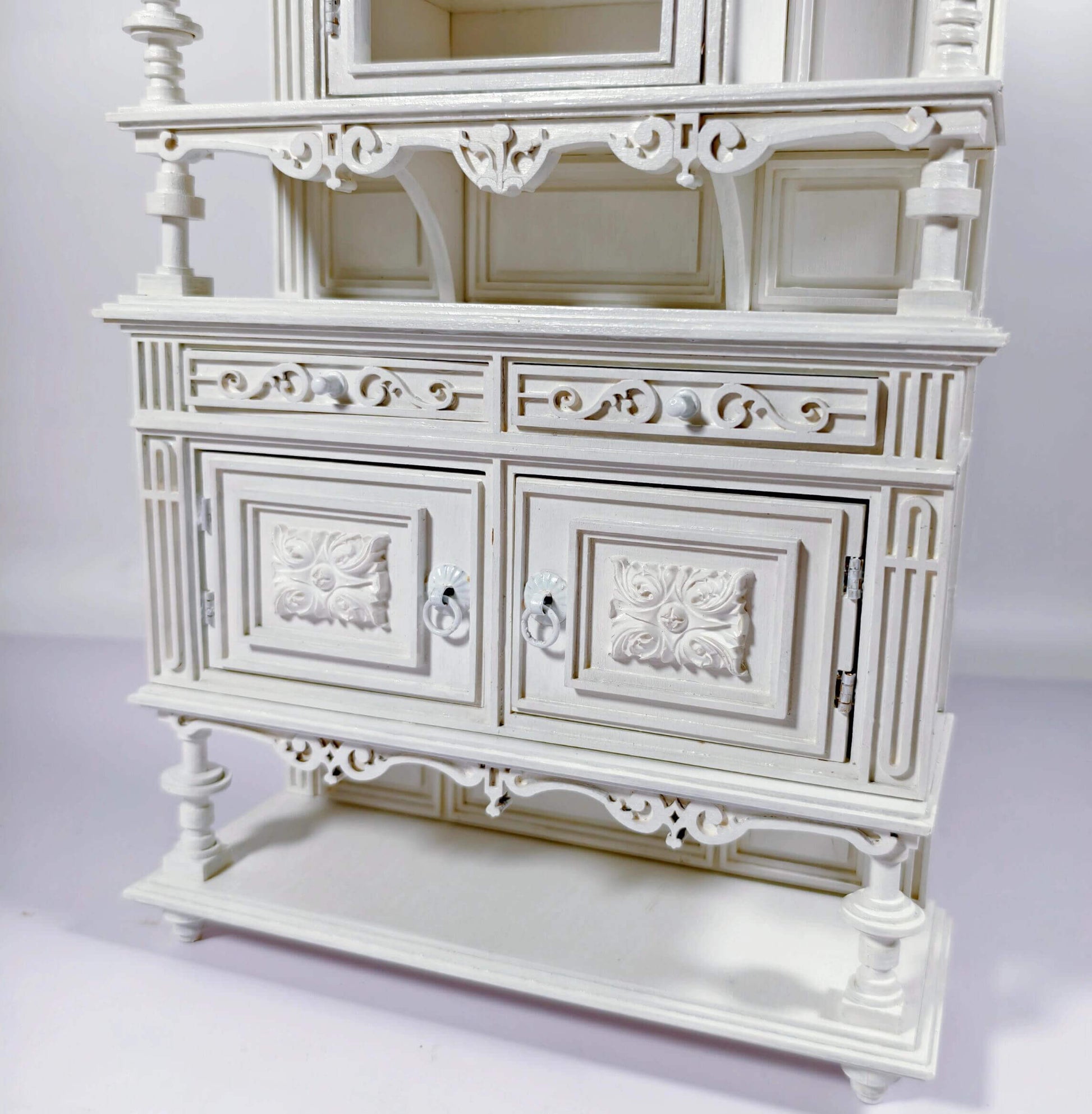 Enhance your dollhouse dining area with this Miniature Antique Buffet Cabinet with Carved and Shelves Kit. This beautifully crafted buffet features both open shelves for displaying miniatures and closed compartments for storage, all adorned with intricately carved decorative details and an elegant design. Available in various sizes, this buffet is perfect for showcasing fine dining accessories, storing dishes, or adding a sophisticated, vintage touch to your miniature kitchen or dining room.