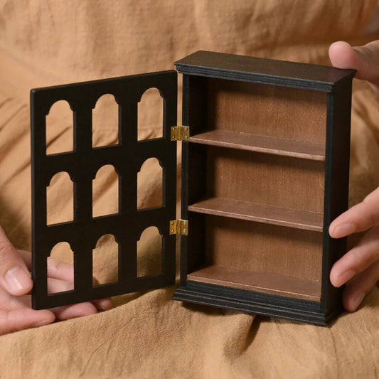 Add a touch of elegance and functionality to your dollhouse with this Miniature Black Wooden Display Cabinet Kit. Featuring arched doors and multiple shelves, this cabinet is perfect for displaying miniature collectibles, spices, or decorative items. The detailed craftsmanship and vintage-inspired design make it a standout piece for any miniature collection.