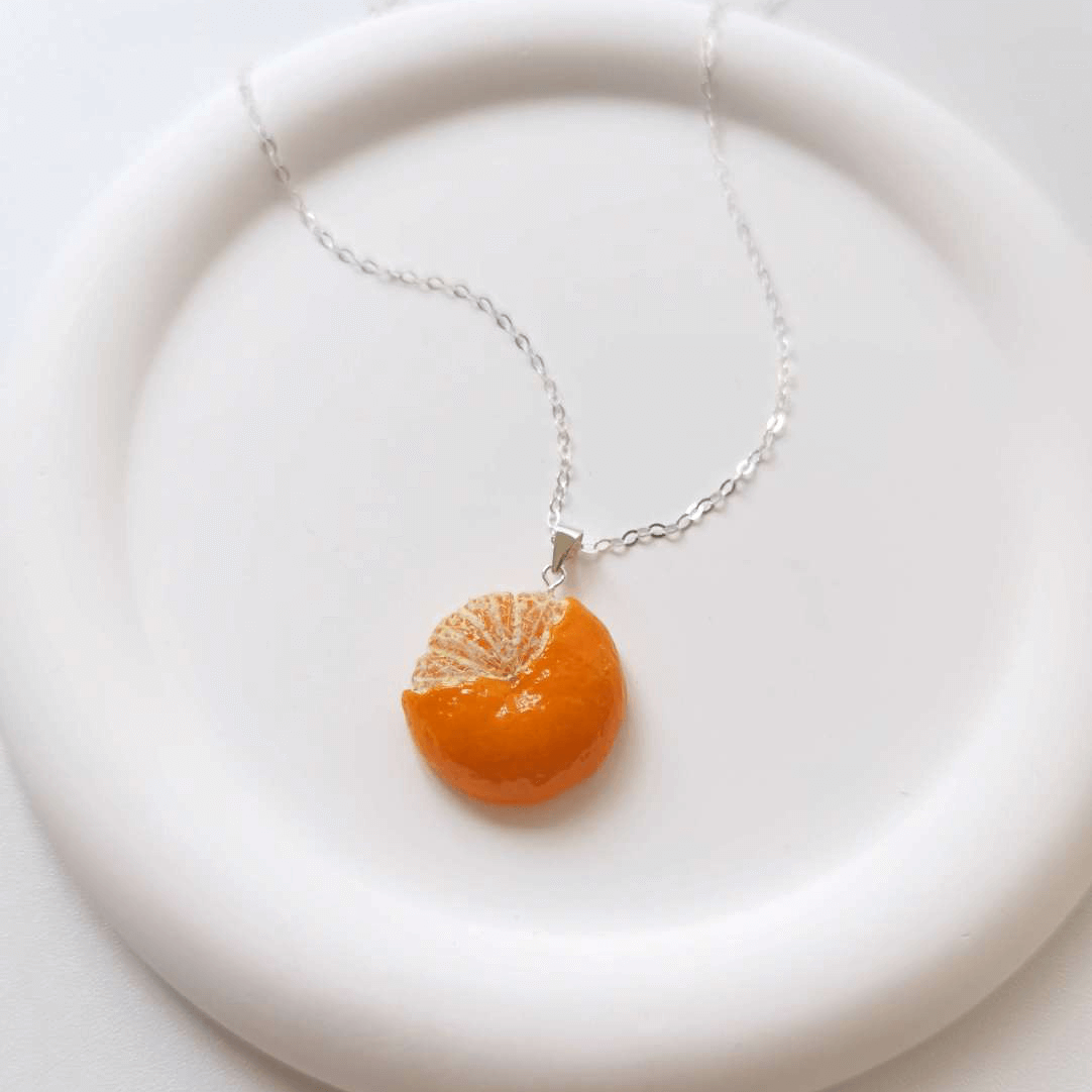 Cute realistic half-peeled tangerine necklace with sterling silver chain. The tangerine are made with polymer clay and then finished with a gloss varnish. The necklace are made from high-quality materials and are durable, but should not be put in aggressive environments like excessive moisture, chemicals or perfume.