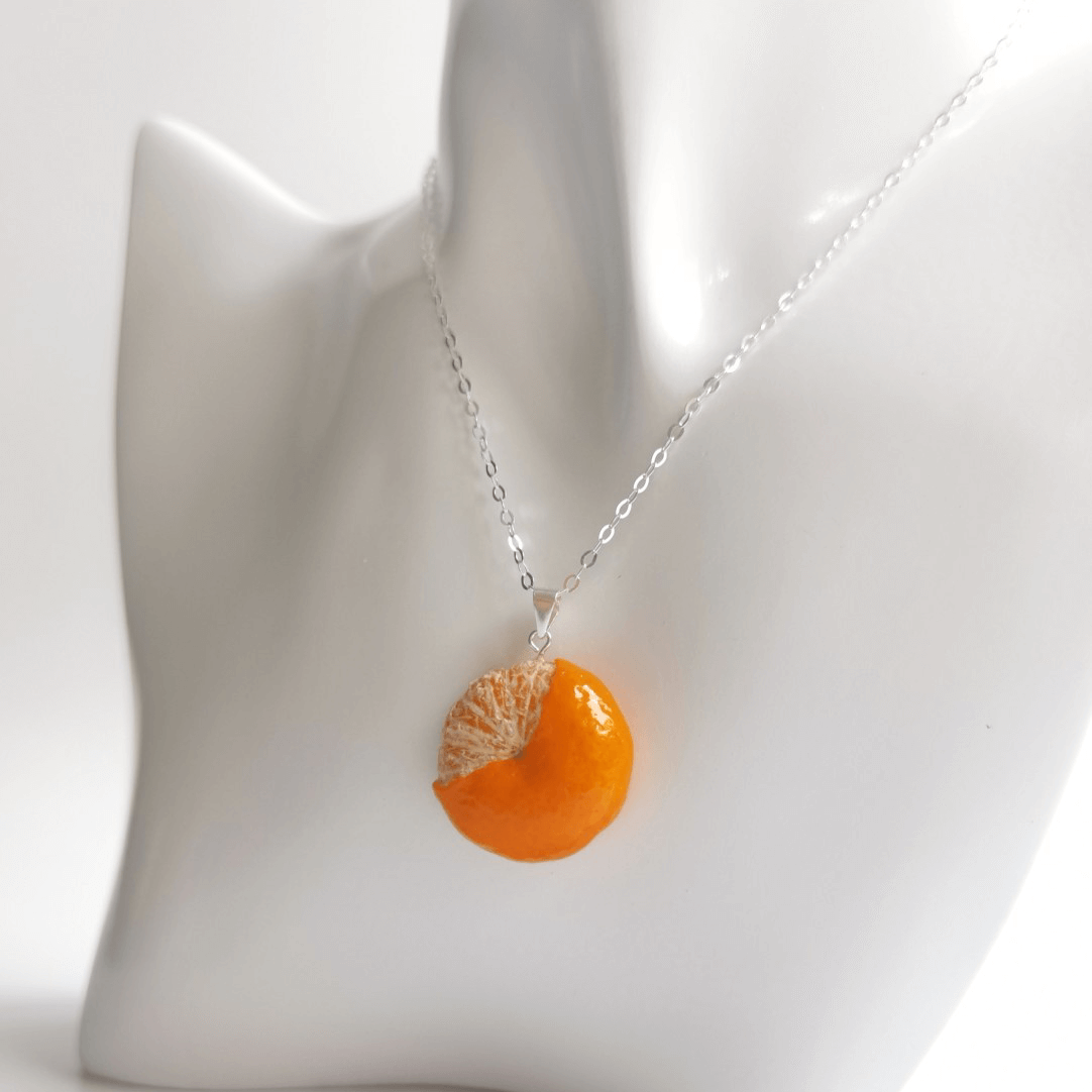 Cute realistic half-peeled tangerine necklace with sterling silver chain. The tangerine are made with polymer clay and then finished with a gloss varnish. The necklace are made from high-quality materials and are durable, but should not be put in aggressive environments like excessive moisture, chemicals or perfume.