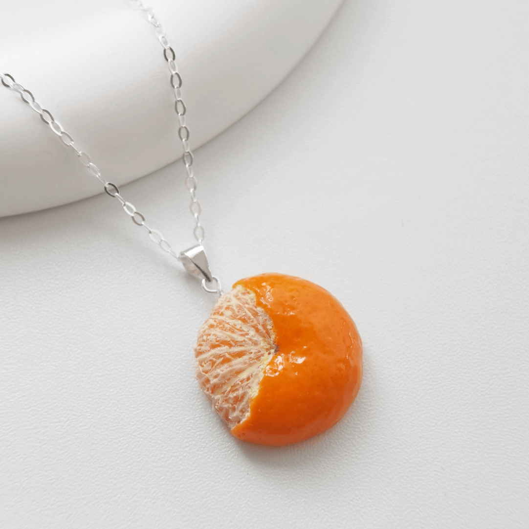 Cute realistic half-peeled tangerine necklace with sterling silver chain. The tangerine are made with polymer clay and then finished with a gloss varnish. The necklace are made from high-quality materials and are durable, but should not be put in aggressive environments like excessive moisture, chemicals or perfume.