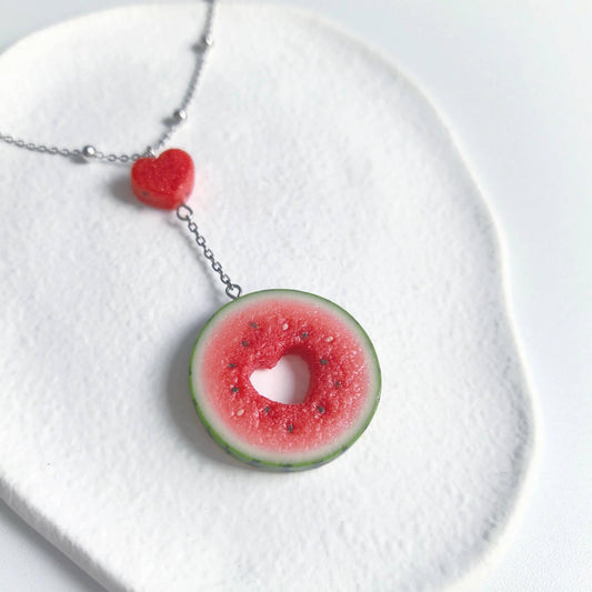 Cute realistic round watermelon slice with cut in the shape of heart necklace with sterling silver chain. The watermelon are made with polymer clay and then finished with a gloss varnish. The necklace are made from high-quality materials and are durable, but should not be put in aggressive environments like excessive moisture, chemicals or perfume.